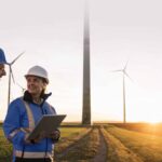 engineers wearing hardhats discussing at sunset