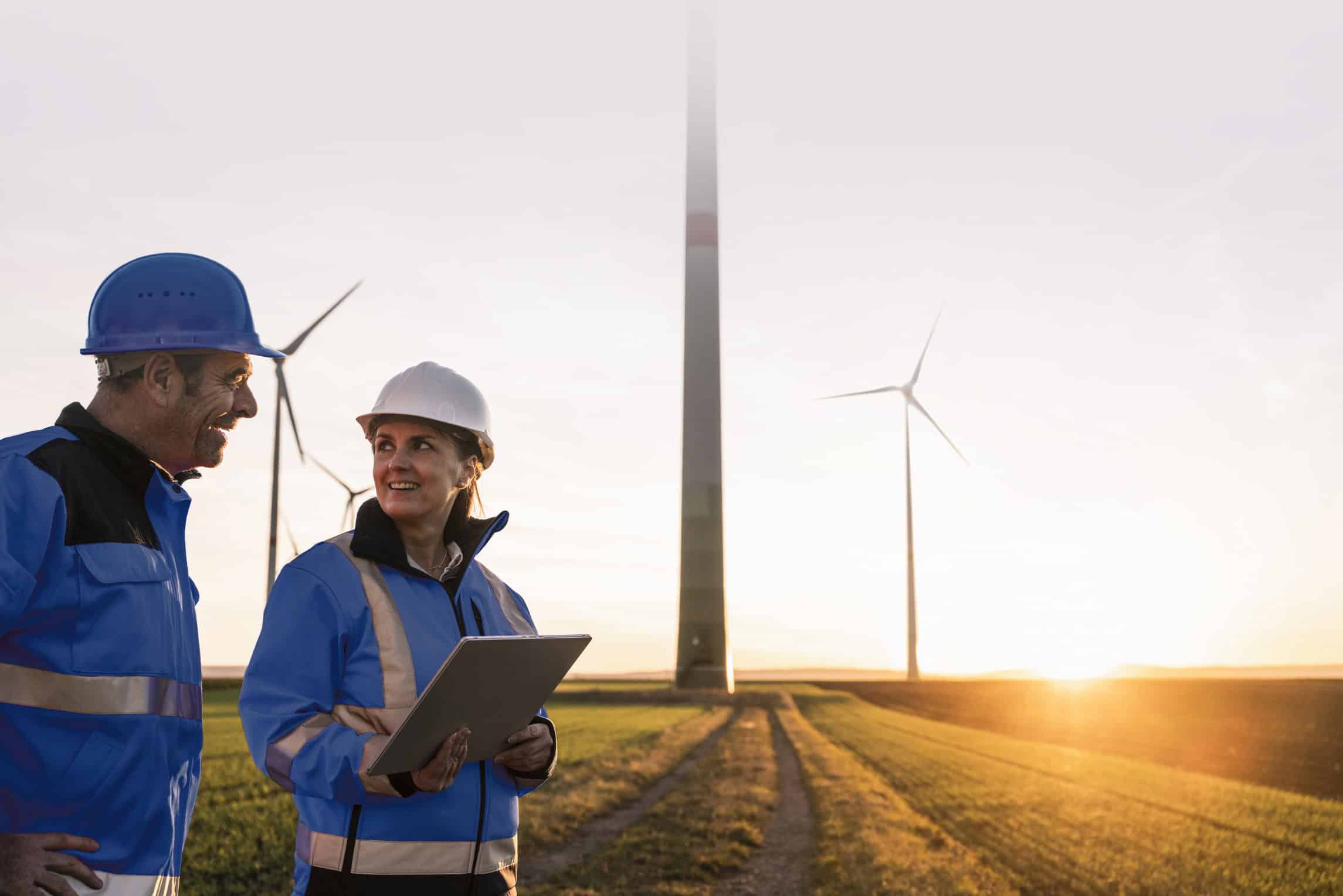 engineers wearing hardhats discussing at sunset